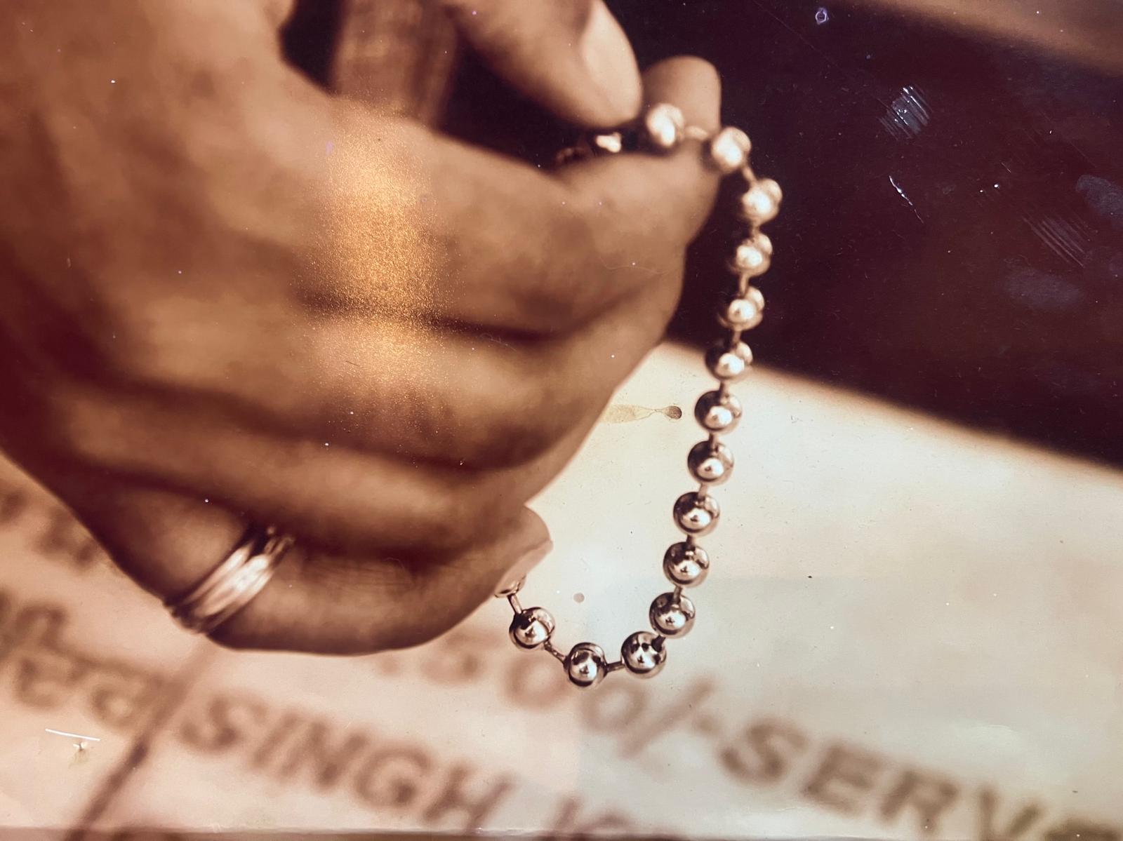 Sundeep's hands holding a beaded mala bracelet